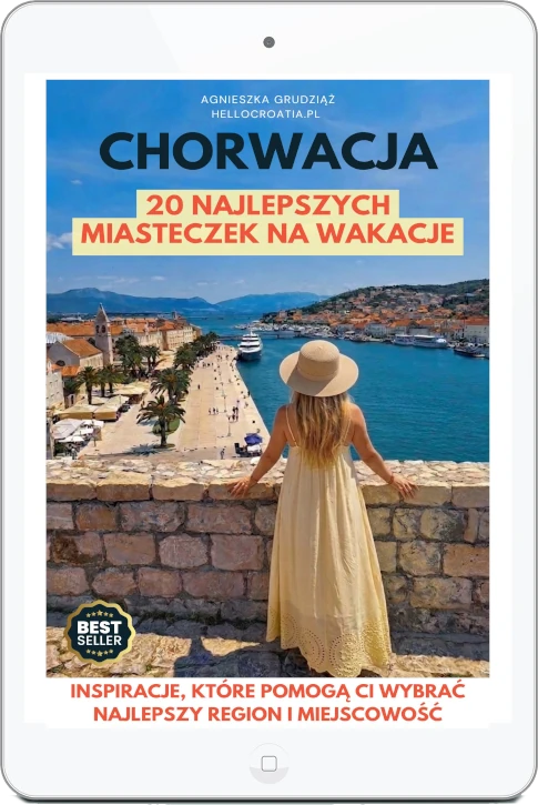 Okładka e-booka „Chorwacja. 20 najlepszych miasteczek na wakacje” Agnieszki Grudziąż (Cromania.pl / HelloCroatia.pl) na ekranie tabletu, przedstawiająca kobietę w kapeluszu patrzącą na nadmorskie miasteczko.